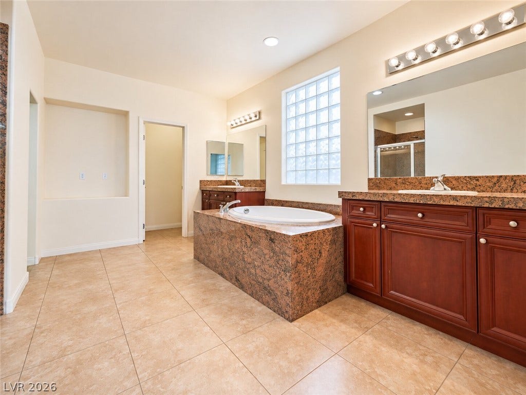 669 Doubleshot Lane, Henderson, NV 89052 Stone counters, a central soaking tub, and tile floors define this main bath retreat.