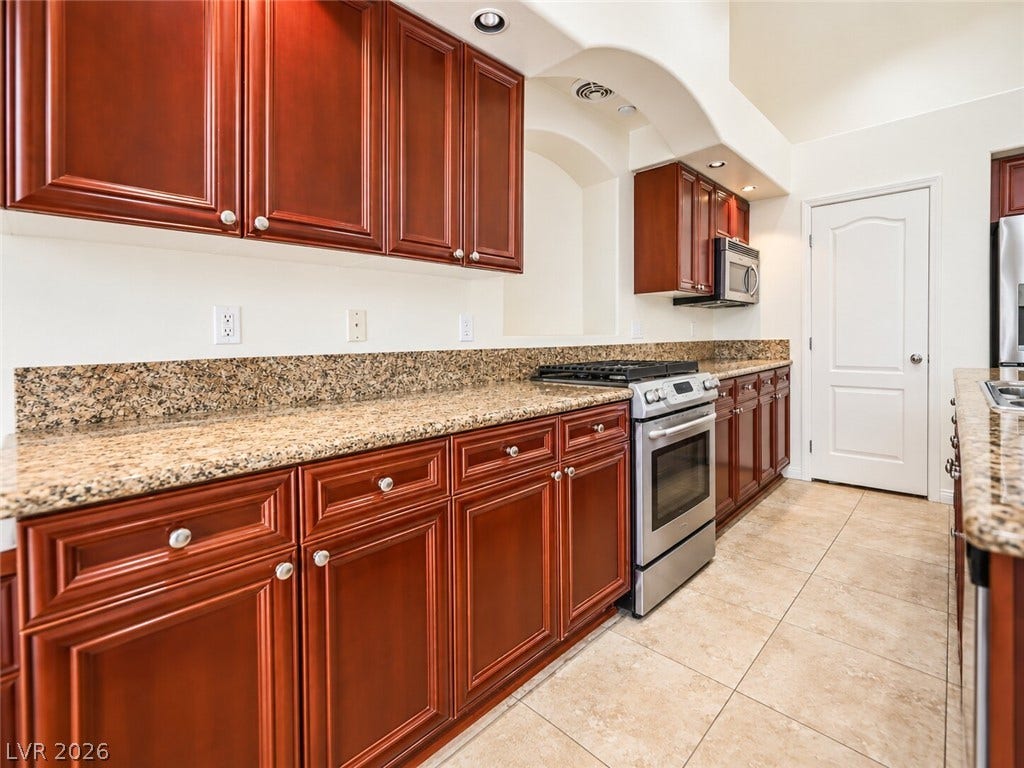 669 Doubleshot Lane, Henderson, NV 89052 Granite countertops and warm wood cabinetry complement the spacious tile flooring in this kitchen.