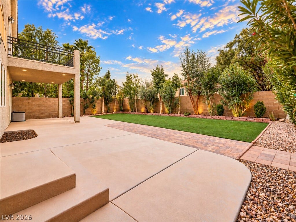 669 Doubleshot Lane, Henderson, NV 89052 A spacious backyard showcases a manicured lawn alongside an expansive concrete and paver patio.