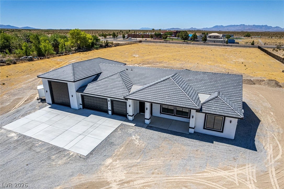 5910 E Kellogg Road, Pahrump, NV 89061 A striking modern exterior features a tiled roof and expansive concrete driveway under desert skies.