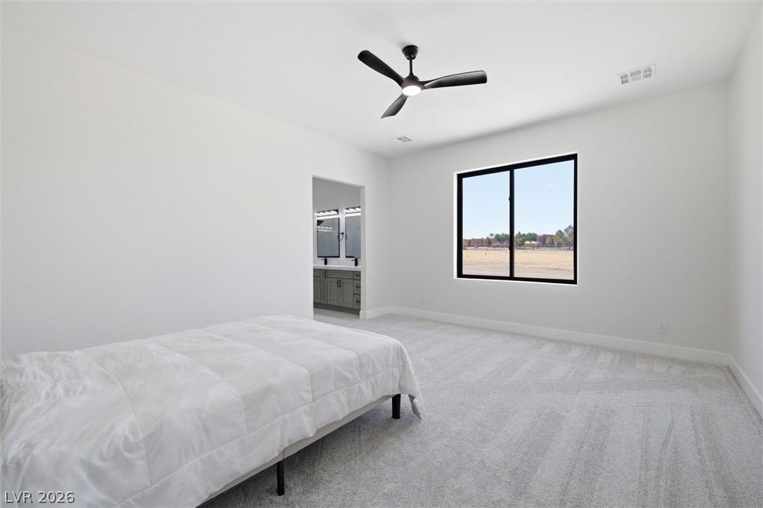 5910 E Kellogg Road, Pahrump, NV 89061 Plush carpeting and a large window framing desert views enhance this minimalist bedroom retreat.
