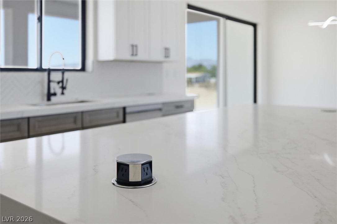 5910 E Kellogg Road, Pahrump, NV 89061 Polished stone countertops integrate convenient pop-up electrical outlets within this modern culinary space.