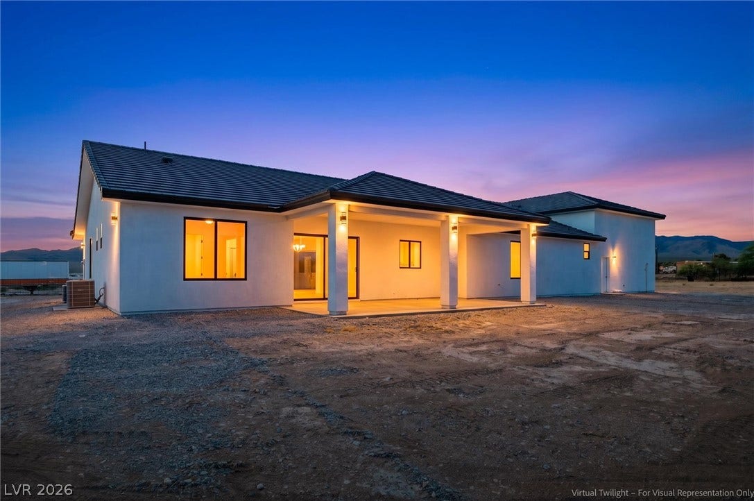 5910 E Kellogg Road, Pahrump, NV 89061 Warmly lit exterior showcases a covered back porch against a colorful twilight sky.