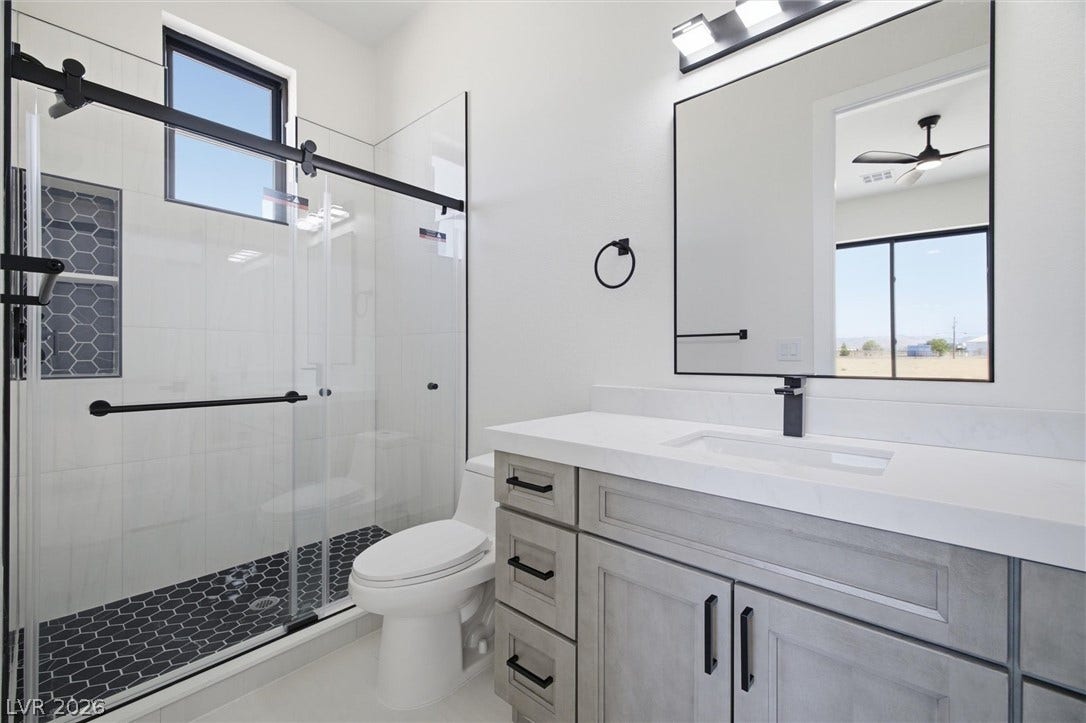 5910 E Kellogg Road, Pahrump, NV 89061 A glass-enclosed walk-in shower highlights this modern washroom with stone countertops.
