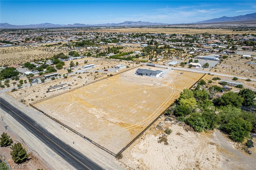 5910 E Kellogg Road, Pahrump, NV 89061 An expansive fenced lot surrounds a single-story residence set against a majestic mountain backdrop.