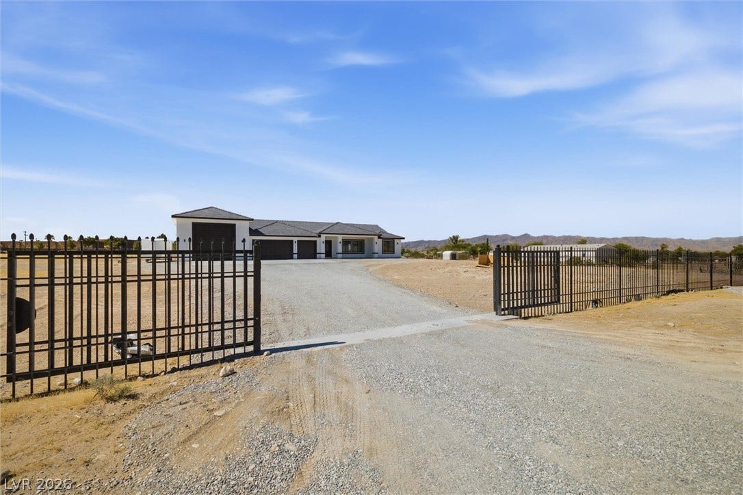 5910 E Kellogg Road, Pahrump, NV 89061 A secure gated entrance leads up a spacious gravel driveway toward the custom home.