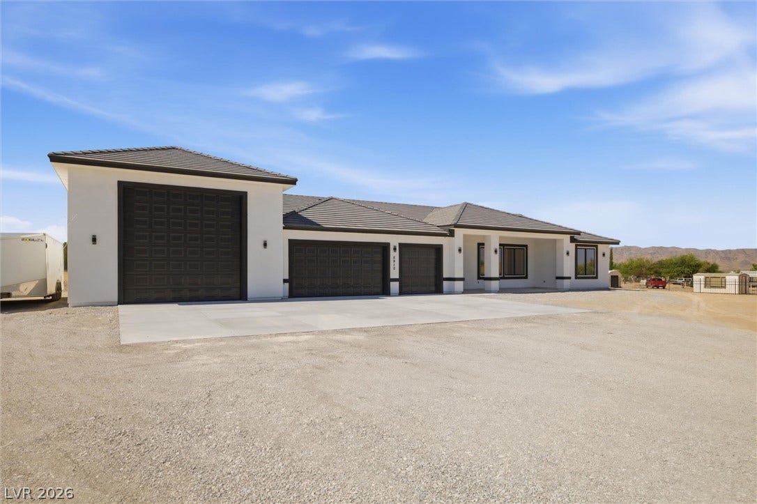 5910 E Kellogg Road, Pahrump, NV 89061 A spacious driveway and multi-car garage setup front a modern single-story desert home.