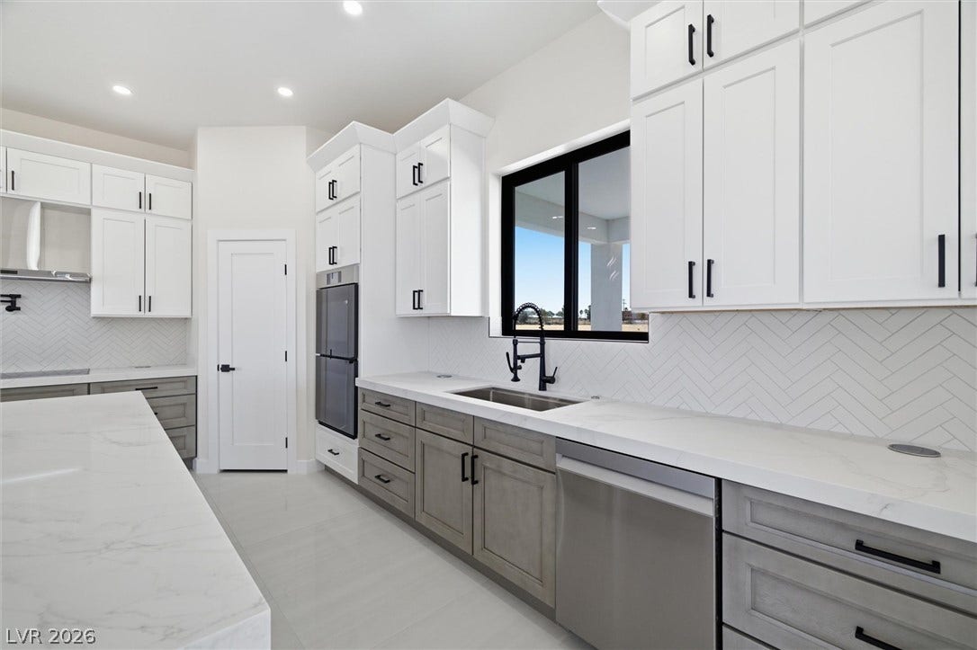 5910 E Kellogg Road, Pahrump, NV 89061 Herringbone backsplash tile and polished stone countertops elevate this contemporary culinary workspace.