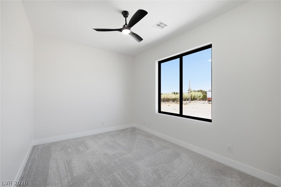 5910 E Kellogg Road, Pahrump, NV 89061 Plush carpeting and a large window framing desert views anchor this versatile secondary bedroom.
