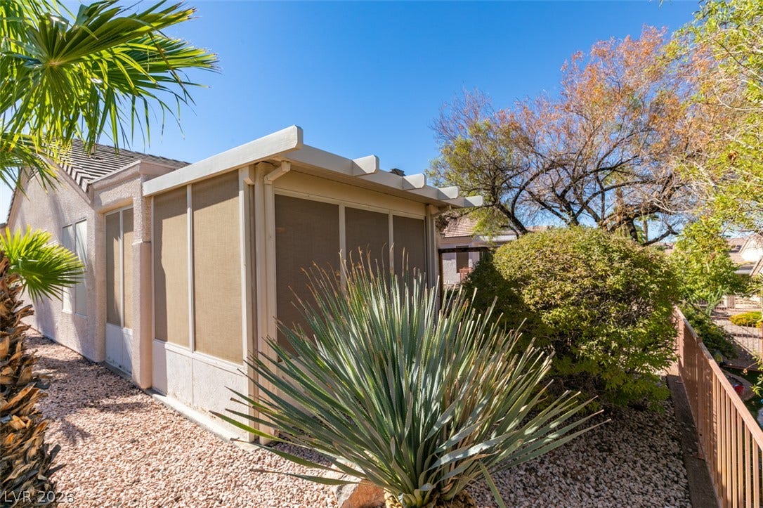 A screened patio structure offers a comfortable outdoor retreat amidst low-maintenance desert landscaping.