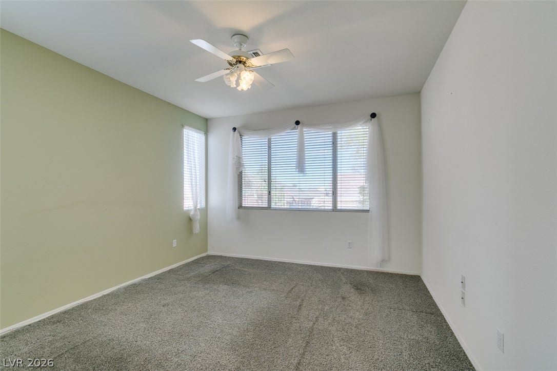 Plentiful natural light streams through large windows into this carpeted bedroom.