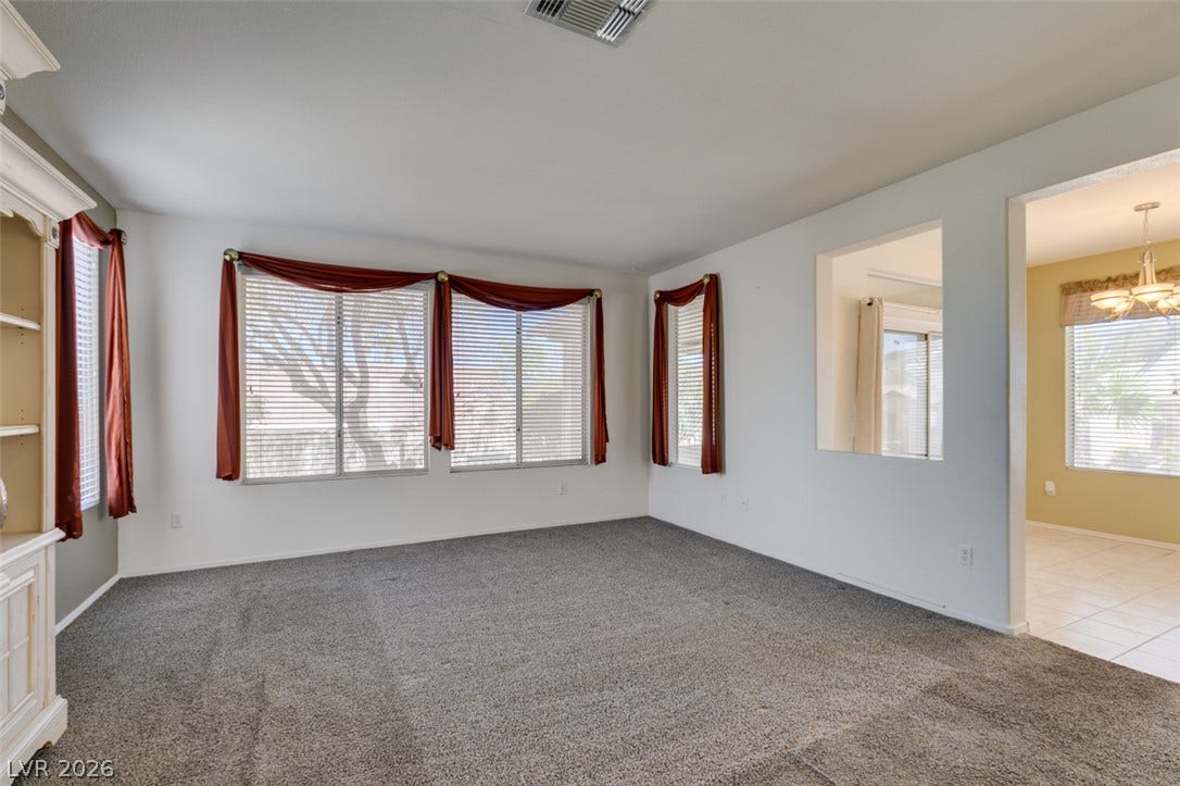 Generous windows fill this carpeted living area with natural light.