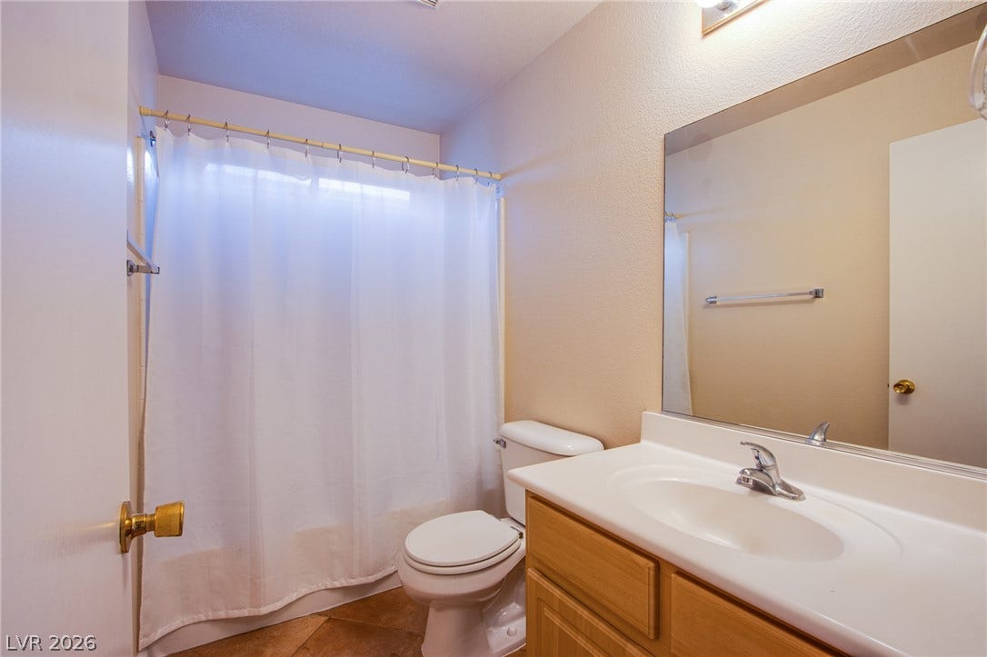 6717 Lookout Lodge Lane, #1, North Las Vegas, NV 89084 A classic bathroom featuring a wood vanity and neutral tile flooring.