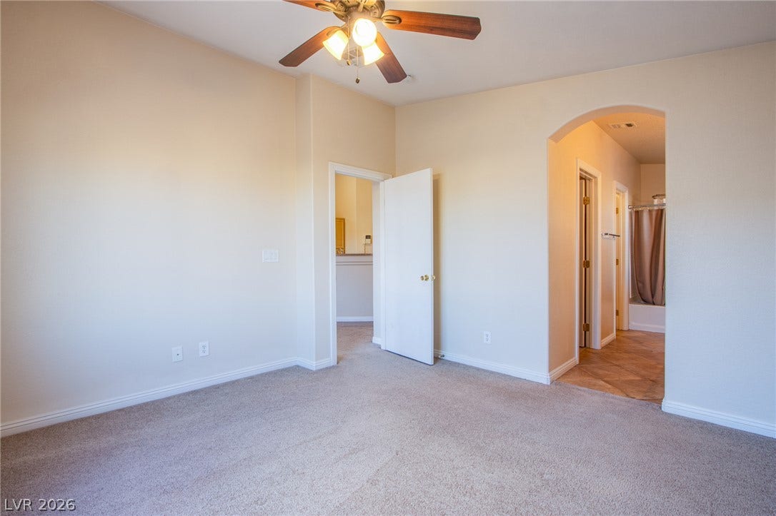 6717 Lookout Lodge Lane, #1, North Las Vegas, NV 89084 Plush carpeting anchors this spacious bedroom featuring an arched doorway leading to the bathroom.