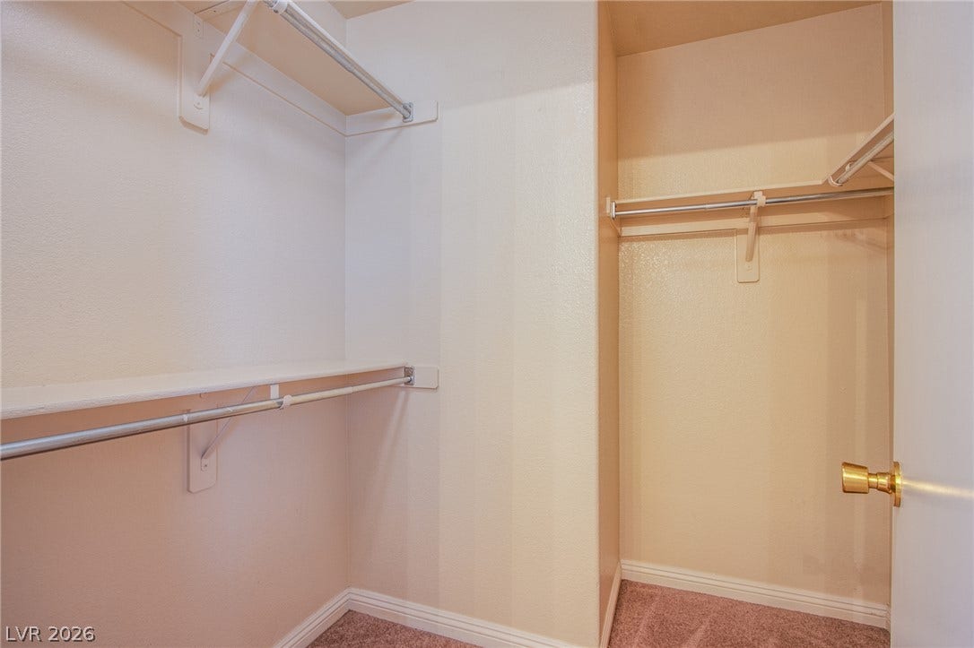 6717 Lookout Lodge Lane, #1, North Las Vegas, NV 89084 Ample storage options define this practical walk-in closet featuring carpeted flooring and built-in shelving.