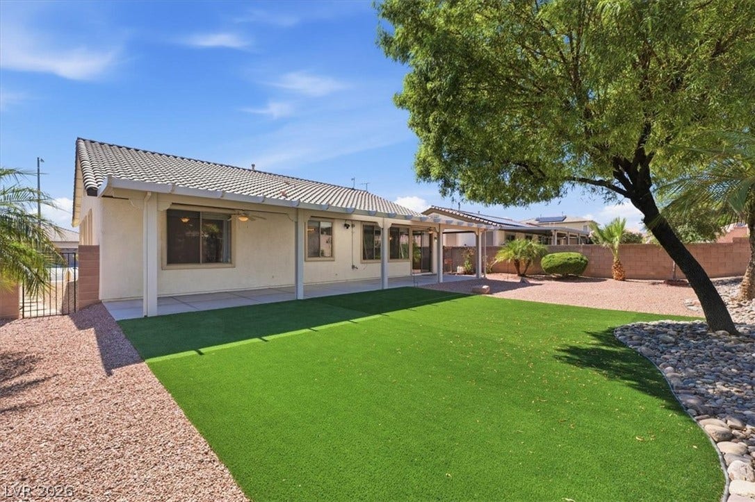 A spacious covered patio overlooks the manicured lawn and low-maintenance desert landscaping.
