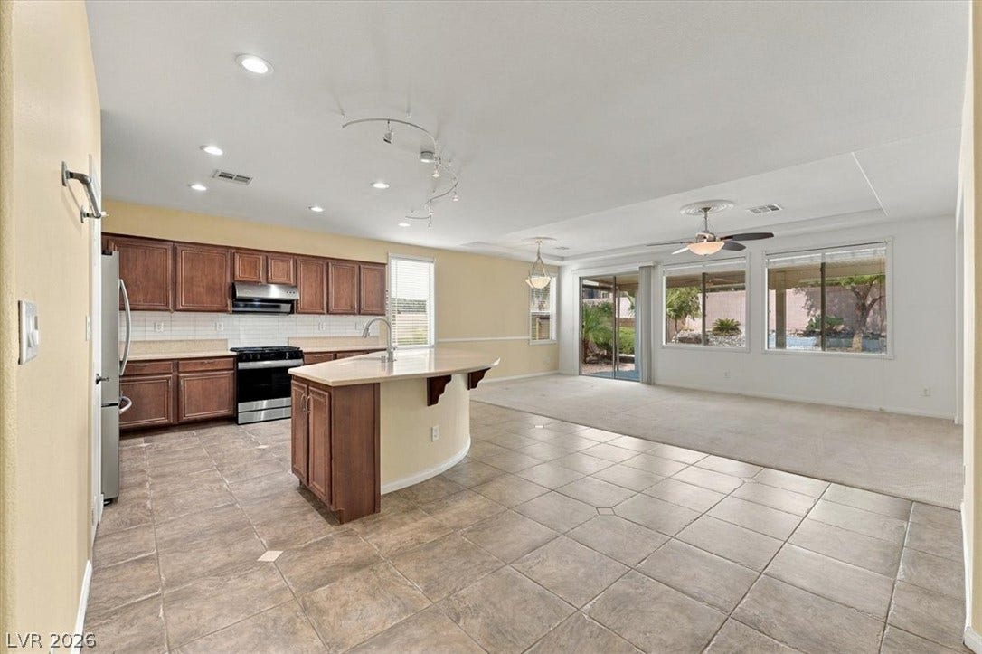 An open floorplan seamlessly connects the tile-floored kitchen and carpeted living space.
