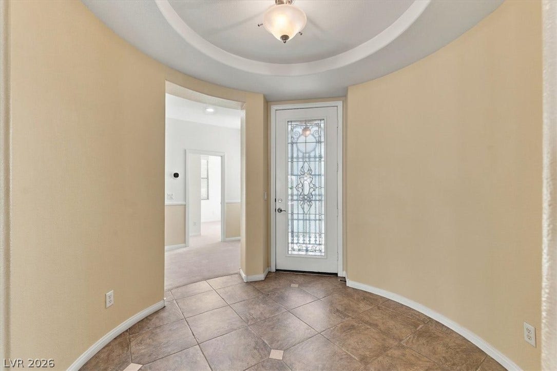 An elegant circular rotunda foyer features curved walls, tile flooring, and a decorative tray ceiling.