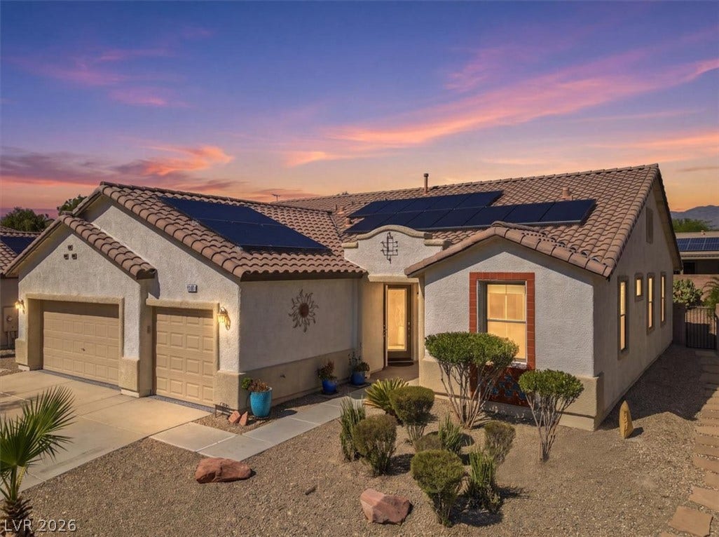 Spanish tile roofing and modern solar panels highlight this desert-landscaped single-story home.