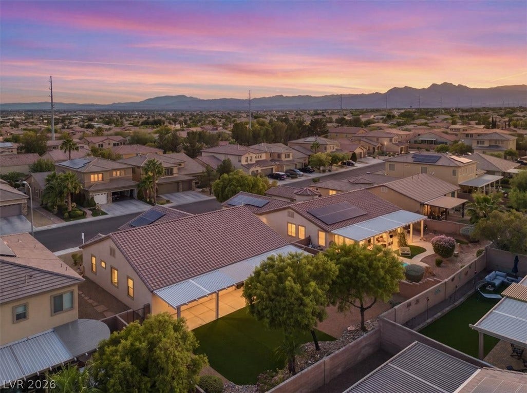 Distant mountains frame a vast neighborhood view under a colorful twilight sky.