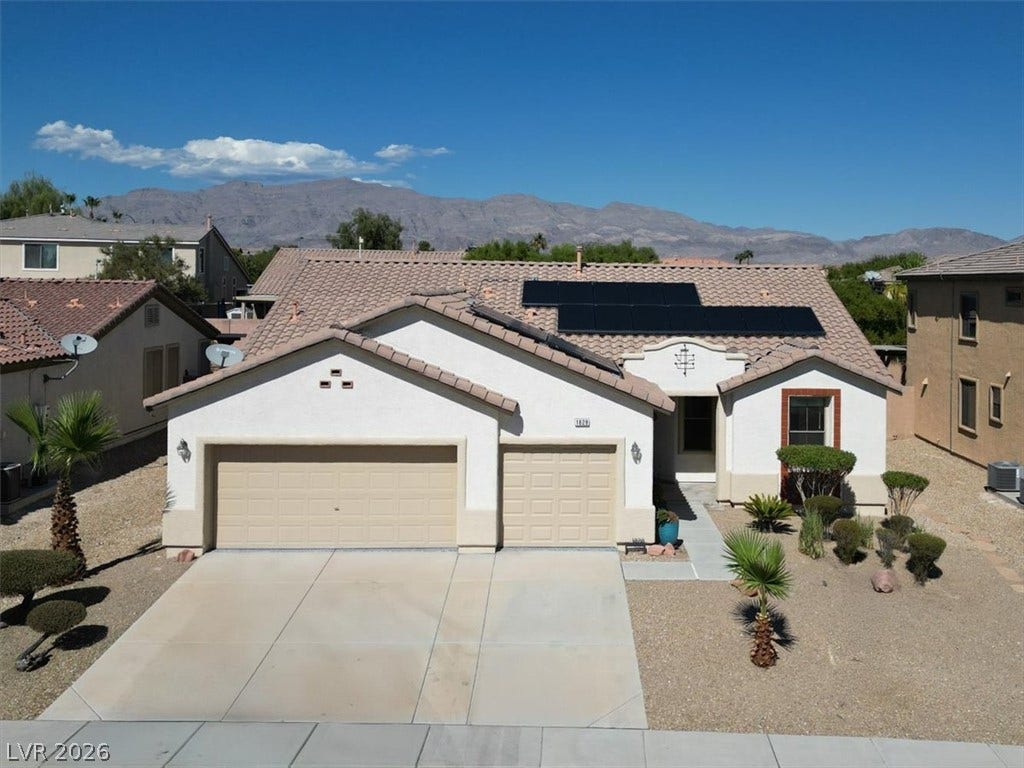 Solar panels accent the tiled roof of this desert-landscaped home set against mountain backdrops.