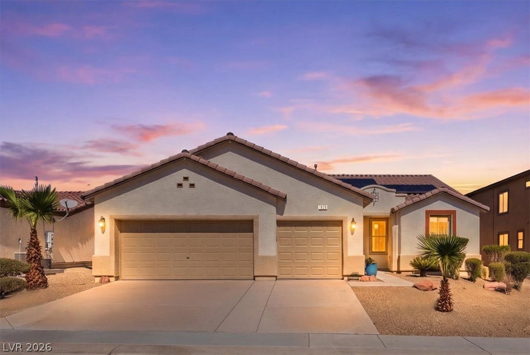 Desert landscaping and a paved driveway complement this classic stucco exterior at sunset.
