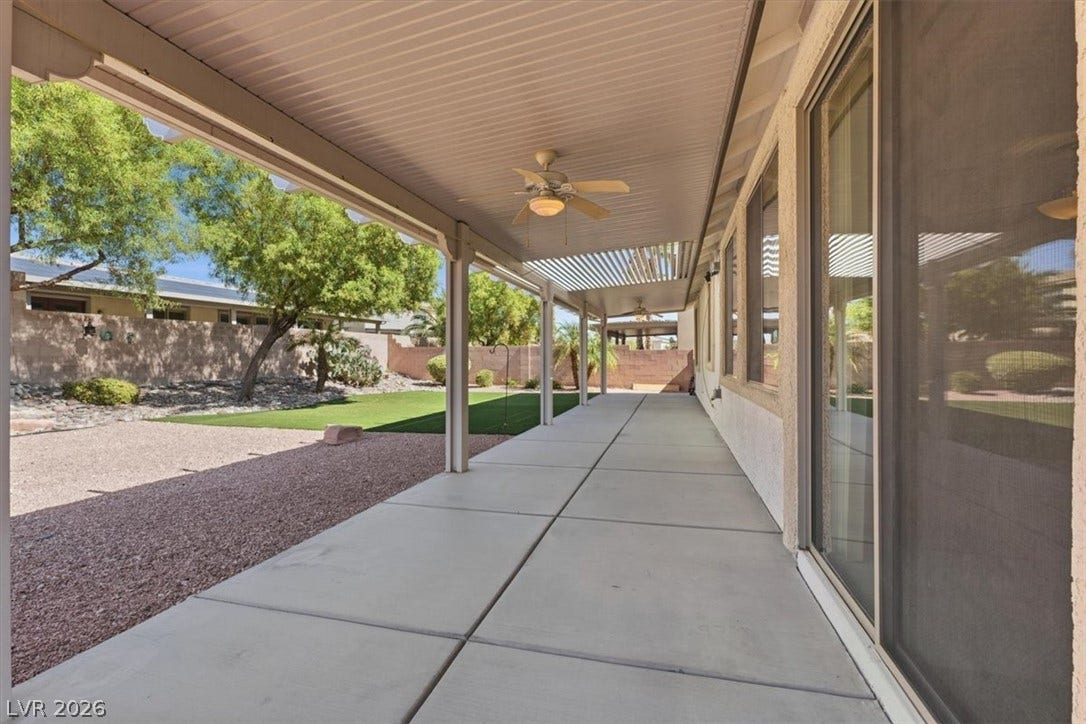 A long concrete patio provides sheltered outdoor living space overlooking the landscaped yard.