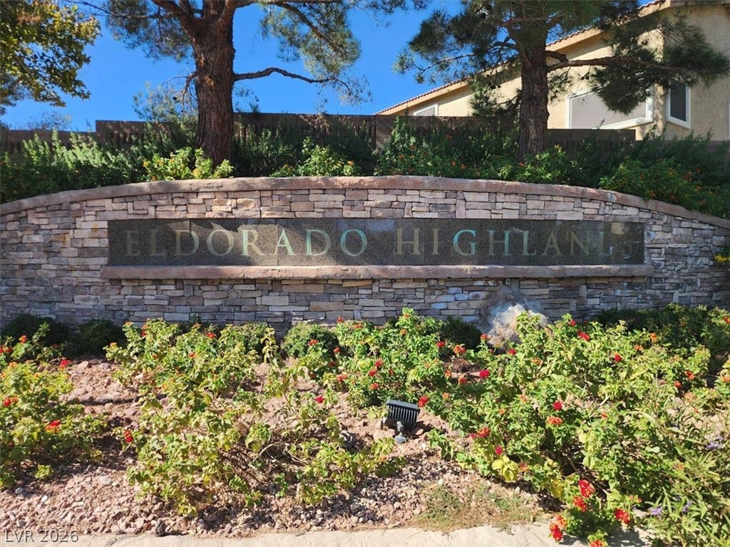 A stone monument sign marks the entrance to this established community surrounded by mature landscaping.