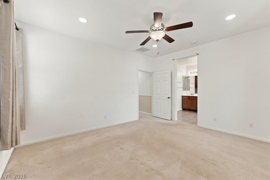 Plush carpeting anchors this spacious bedroom featuring an attached private bathroom.