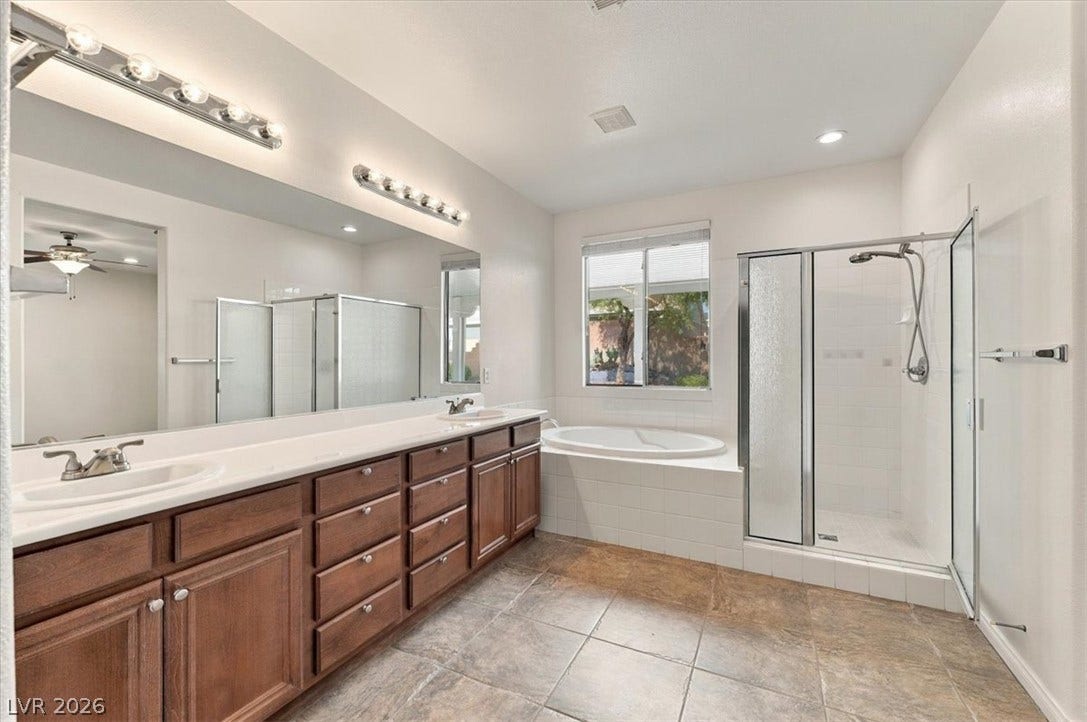 Tile flooring complements a double vanity, soaking tub, and separate glass-enclosed shower.
