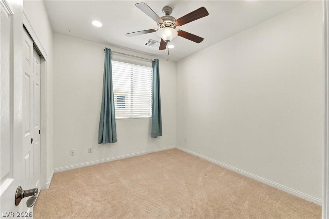 A windowed secondary bedroom features wall-to-wall carpeting and neutral-colored walls.