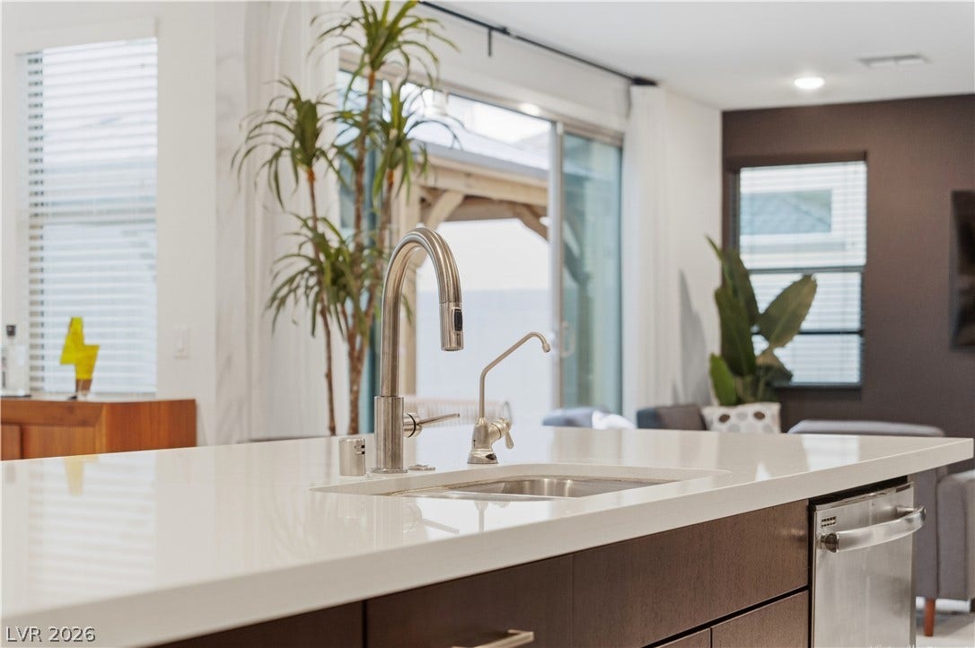 544 Front Range Lane, North Las Vegas, NV 89084 A sleek kitchen island features smooth stone countertops and integrated dual stainless steel sinks.