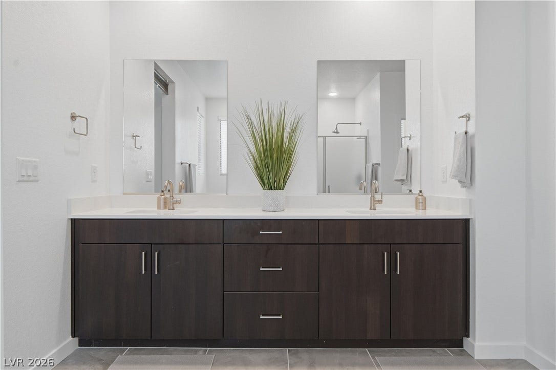 544 Front Range Lane, North Las Vegas, NV 89084 A spacious double vanity anchors this modern bathroom featuring dark cabinetry and tiled flooring.