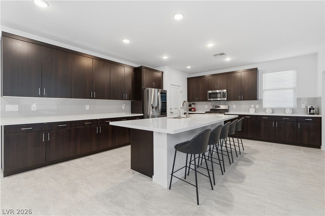 544 Front Range Lane, North Las Vegas, NV 89084 Rich dark cabinetry contrasts beautifully with white stone countertops and a spacious central island.