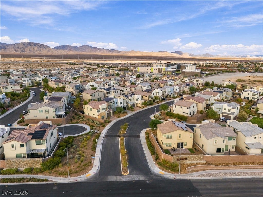 544 Front Range Lane, North Las Vegas, NV 89084 Paved neighborhood streets wind through a modern residential community set against a rugged mountain backdrop.
