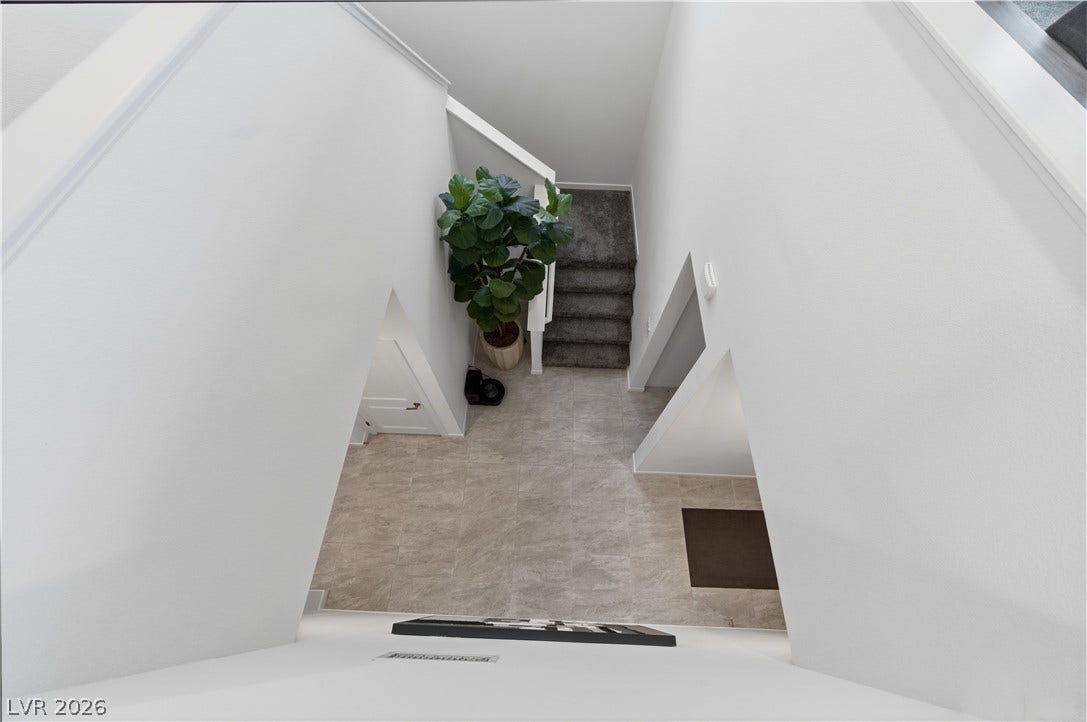 544 Front Range Lane, North Las Vegas, NV 89084 An aerial perspective showcases a tiled entryway transitioning to carpeted stairs and clean white walls.