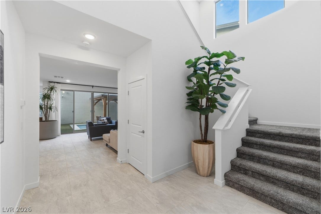 544 Front Range Lane, North Las Vegas, NV 89084 A bright entryway features tiled floors and carpeted stairs leading upward.
