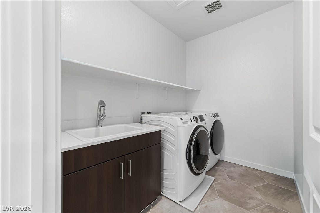 544 Front Range Lane, North Las Vegas, NV 89084 Functional laundry space showcases durable tile flooring alongside a practical utility sink and cabinetry.
