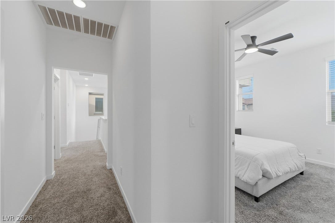 544 Front Range Lane, North Las Vegas, NV 89084 Smooth plaster walls and neutral carpeting span this modern upper-level hallway leading to a bedroom.