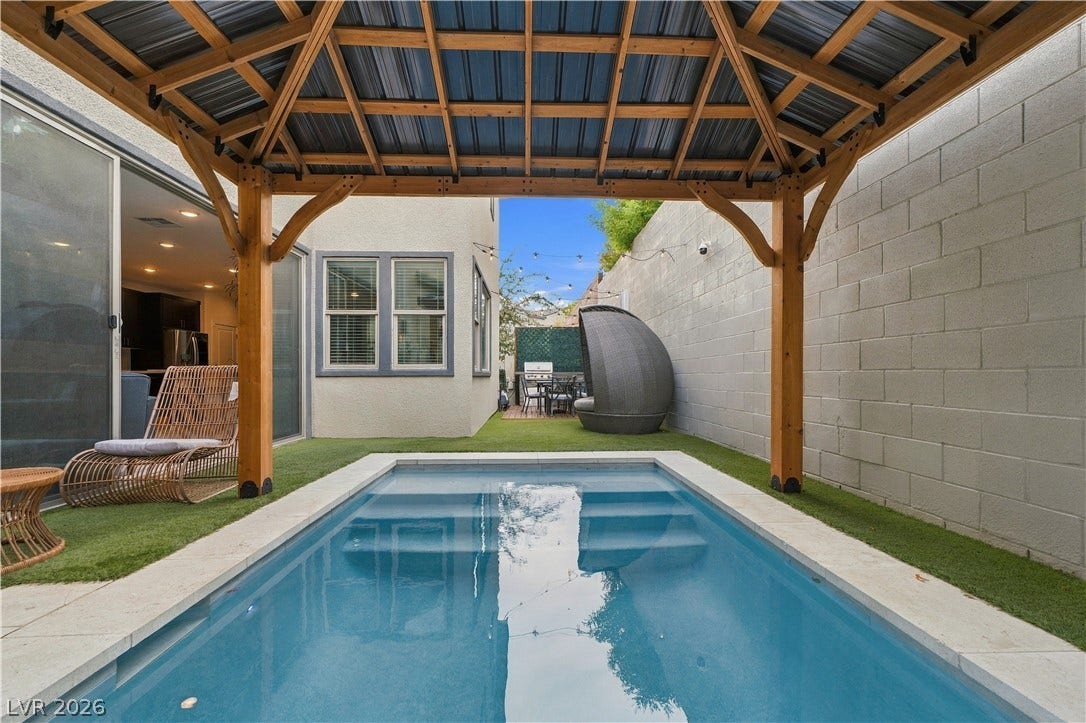 544 Front Range Lane, North Las Vegas, NV 89084 An inviting backyard pool area rests beneath a wooden pavilion next to a stone-walled courtyard.