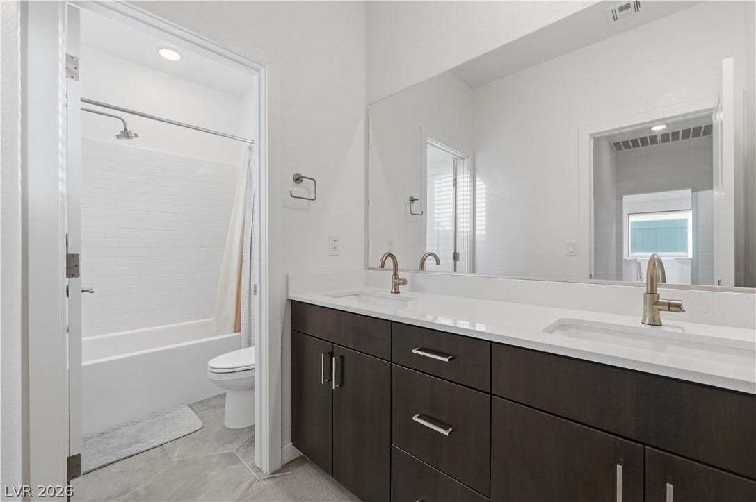 544 Front Range Lane, North Las Vegas, NV 89084 A double vanity with dark cabinetry sits adjacent to the tiled guest bathroom.