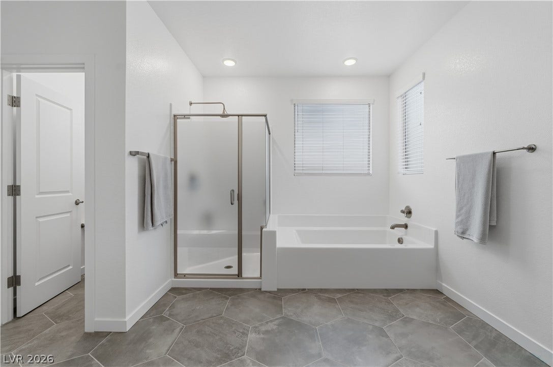 544 Front Range Lane, North Las Vegas, NV 89084 Geometric floor tile and recessed lighting complement a glass-enclosed shower and adjacent soaking tub.