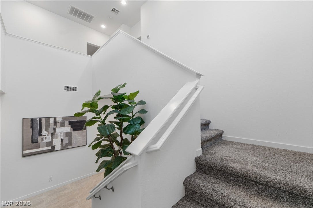 544 Front Range Lane, North Las Vegas, NV 89084 Carpeted stairs ascend past clean white walls and a bright upper landing.