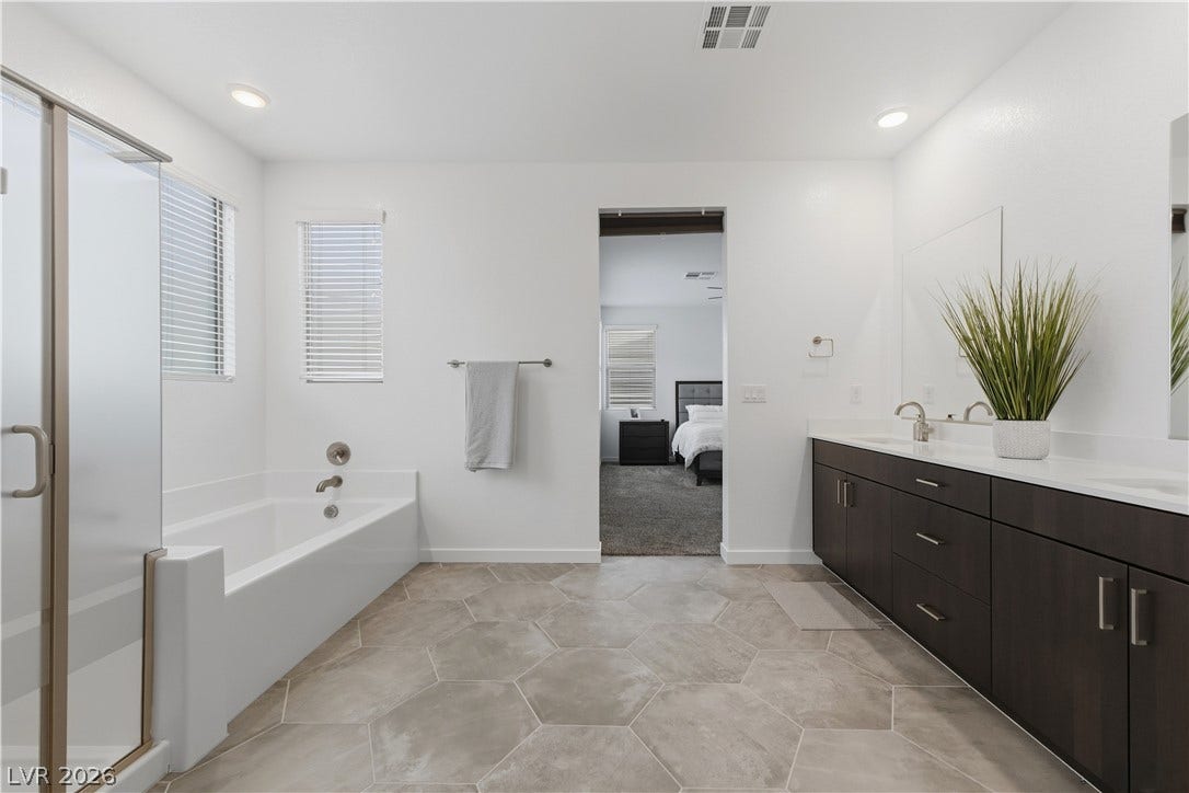544 Front Range Lane, North Las Vegas, NV 89084 Geometric floor tile and a deep soaking tub anchor this tranquil primary bathroom.