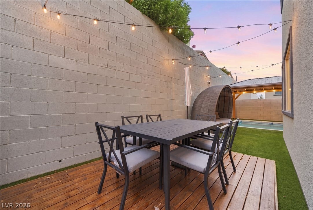 544 Front Range Lane, North Las Vegas, NV 89084 A wooden deck steps down to a green lawn area beside a tall block wall.