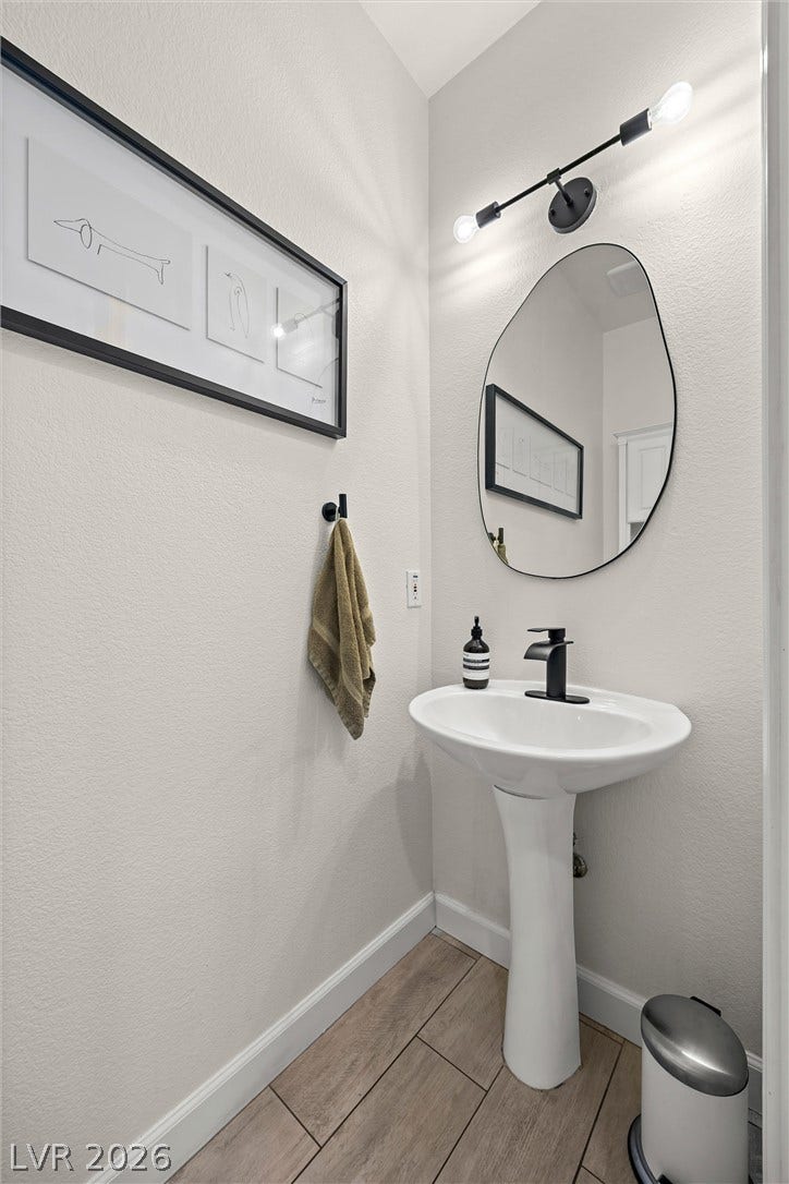 1421 Dragon Rock Drive, Henderson, NV 89052 Wood-look tile flooring paired with a classic white pedestal sink anchors this modern powder room.