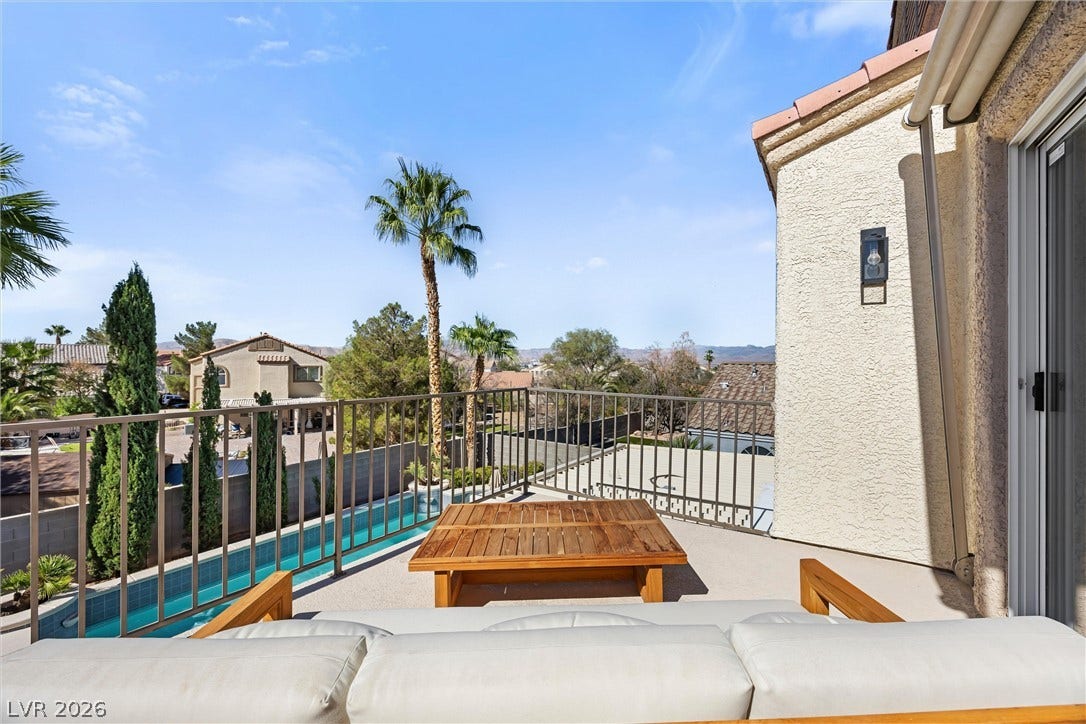 1421 Dragon Rock Drive, Henderson, NV 89052 An elevated private balcony overlooks a sparkling lap pool surrounded by mature palm trees.