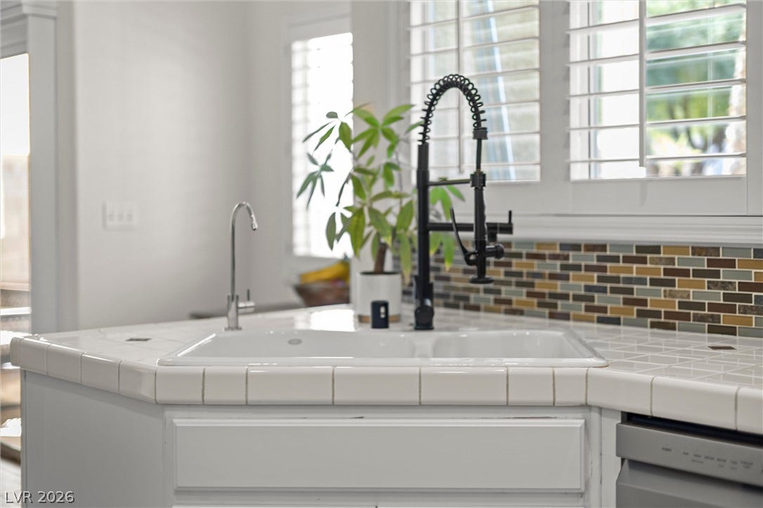 1421 Dragon Rock Drive, Henderson, NV 89052 A tiled countertop surrounds a classic kitchen sink beneath plantation shutters.