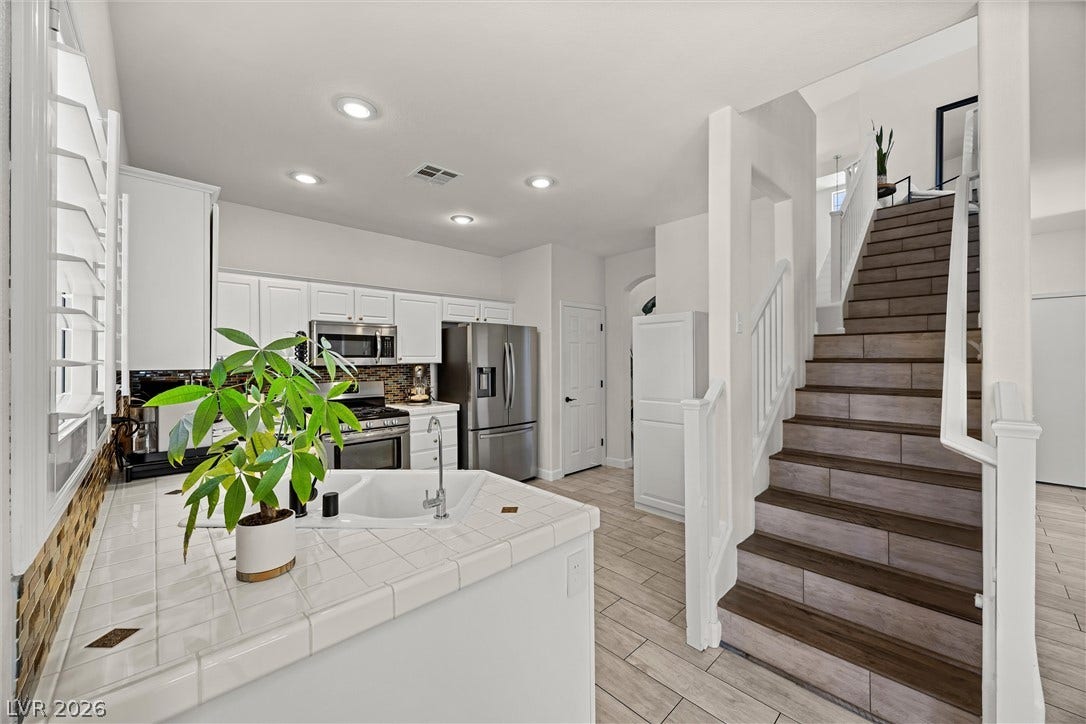 1421 Dragon Rock Drive, Henderson, NV 89052 An open kitchen layout transitions smoothly toward the light-filled staircase with built-in wood-look tile accents.