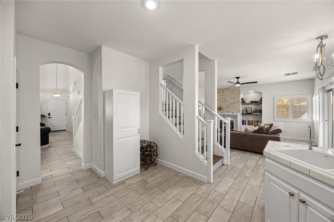 1421 Dragon Rock Drive, Henderson, NV 89052 Wood-look tile flooring connects the central hallway, open-plan living spaces, and split staircase.